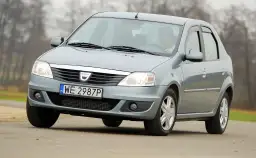 Szary Dacia Logan sedan z polskimi tablicami WE 2987P jedzie po drodze.