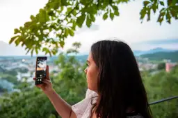 Kobieta robi zdjęcie telefonem, ale widać pogorszenie jakości zdjęć w telefonie.