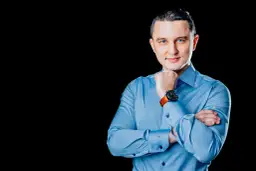 Mężczyzna w niebieskiej koszuli, z rękami skrzyżowanymi na piersi, podczas sesji biznesowej.