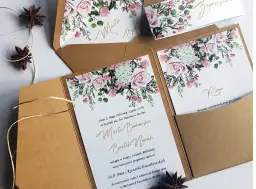 Eleganckie zaproszenia ślubne z motywem róż i zieleni, w brązowych kopertach.
