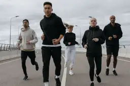 Grupa biegaczy w sportowych strojach. Idealny zestaw, jak się ubrać na bieganie 10 stopni: bluzy, spodnie i kurtki.