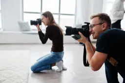 Mężczyzna i kobieta uczą się, jak zostać fotografem, ćwicząc z aparatami w studiu.
