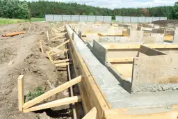 Budowa fundamentów pod dom szkieletowy. Betonowe ławy i szalunki drewniane tworzą solidną podstawę.