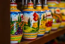 Kolorowe, ręcznie malowane butelki z motywami włoskiego krajobrazu. Idealne, by znaleźć gdzie kupić pamiątki w Rzymie.