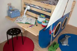 Biurko z łóżkiem w kształcie statku, z zabawkami i książką do nauki.