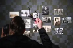 Osoba z słuchawkami na uszach ogląda wystawę zdjęć z czasów wojny. Czy wśród nich jest dziadek Donalda Tuska?