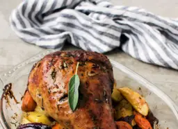 Pieczony udziec z indyka z warzywami korzeniowymi w naczyniu żaroodpornym.