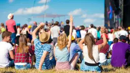 Widok zza pleców na tłum ludzi na jednym z największych festiwali muzycznych w Polsce. Słońce, niebo i dobra zabawa.