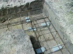 Zbrojenie fundamentów w narożnikach, gotowe do zalania betonem. Widać staranne łączenie zbrojenia w narożnikach.