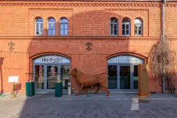 Rzeźba byka przed ceglanym budynkiem z szyldem "Yes Butcher!".