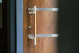 Eleganckie drzwi z meranti z nowoczesnym, metalowym uchwytem i ozdobnymi listwami.