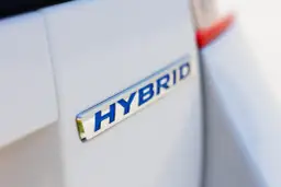 Niebieski napis HYBRID na białym samochodzie.