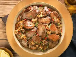 Smażona wątróbka z cebulą i papryczką chili na talerzu.