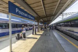 Peron na dworcu Poznań Główny z pociągami i pasażerami.