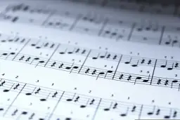 Nuty na papierze, nuty i cyfry. Słowa "tekst piosenki jaki tu spokój" unoszą się w ciszy.