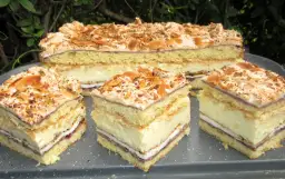 Pychotka przepis na dużą blachę. Warstwowy deser z kremem, dżemem i bezą, posypany migdałami.