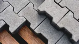 Szare kostki brukowe ułożone na drewnianej palecie. Sprawdź ceny układania kostki brukowej i zaplanuj swój podjazd.