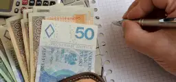 Zasiłek pielęgnacyjny to wsparcie dla osób potrzebujących. Na zdjęciu polskie banknoty, kalkulator i notatnik.