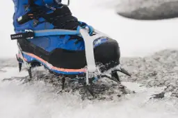 Niebieskie buty górskie z zamontowanymi rakami koszykowymi, gotowe na lodowe wyzwania.