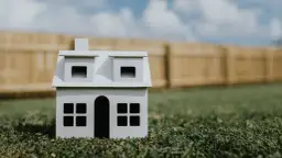 Model domu na trawie, symbolizujący minimalną wielkość działki budowlanej na wsi.