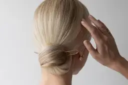 Elegancki kok z wsuwką to jedna z modnych fryzur na wesele. Delikatna biżuteria podkreśla styl.