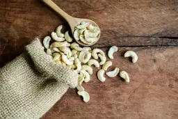 Orzechy nerkowce właściwości: garść zdrowia wysypana z worka na drewniany stół.