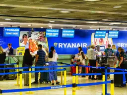 Kasa biletowa i punkty odprawy bagażu Ryanair na lotnisku, z ludźmi i bagażami.