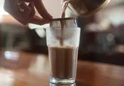 Przelewanie aromatycznego napoju przez sitko do szklanki.