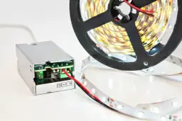 Zasilacz do taśmy LED, który może okazać się za mocny. Rolka taśmy LED i podłączony zasilacz.
