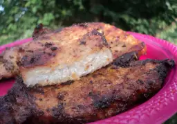 Grillowany schab na różowym talerzu, z widocznym przekrojem mięsa.
