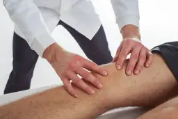 Terapeuta wykonuje delikatne ruchy na nodze pacjenta, co ilustruje, na czym polega terapia Bowen'a.