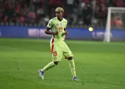 Piłkarz w żółtej koszulce z numerem 19 biegnie po boisku. Może to jeden ze **100 najlepszych piłkarzy na świecie**.