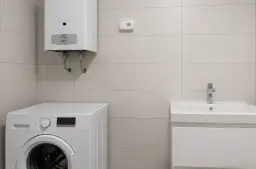 Czujnik czadu zamontowany na ścianie nad pralką i podgrzewaczem wody. W łazience znajduje się też umywalka.