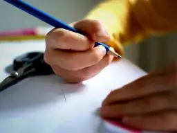 Dziecko pisze kredką, licząc ile dni do końca szkoły. Obok leżą nożyczki.