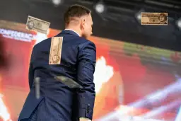 Mężczyzna w garniturze z banknotami na plecach. To wizualizacja programu partii politycznej przykłady, pokazująca inflację.