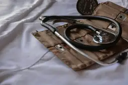 Stetoskop i mankiet ciśnieniomierza na białej tkaninie.