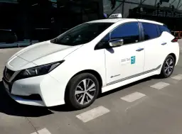 Białe taxi z lotniska Balice, elektryczne, gotowe do jazdy. Zastanawiasz się, ile kosztuje taxi z lotniska Balice do centrum Krakowa?