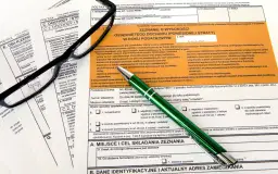 Okulary i zielony długopis leżą na formularzach podatkowych PIT.