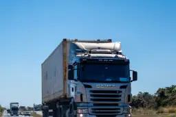 Ciężarówka Scania z kontenerem na autostradzie pod błękitnym niebem.