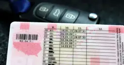 Zbliżenie na polskie prawo jazdy z datami ważności kategorii, obok kluczyki samochodowe. Sprawdź, prawo jazdy na ile lat jest ważne.
