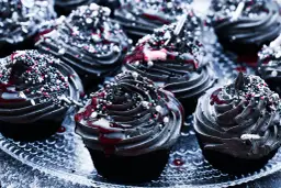 Mroczne muffinki halloween z czarną polewą, czerwonym lukrem i kolorową posypką.