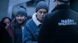 Mężczyzna w czapce i dżinsowej kurtce patrzy na funkcjonariusza Służby Więziennej. Scena z jednego z polskich seriali Canal Plus.