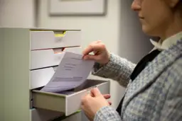Kobieta przegląda dokumenty, szukając informacji, jak napisać apelację do sądu.