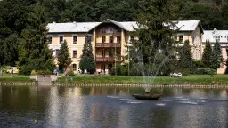Piękny budynek sanatorium godne polecenia, z fontanną i stawem, otoczony zielenią.