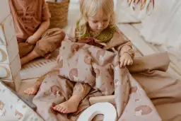 Mała dziewczynka bawi się śpiworem do przedszkola z motywem jeży.