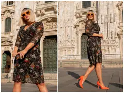 Kobieta w kwiecistej sukience i pomarańczowych szpilkach przed katedrą. Czy buty w kwiaty są modne? Te pomarańczowe zdecydowanie tak!
