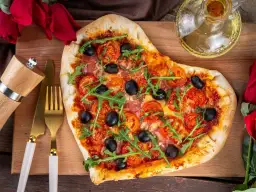 Pizza w kształcie serca z pomidorami, oliwkami i rukolą. Idealna na romantyczną kolację w domu, co ugotować?