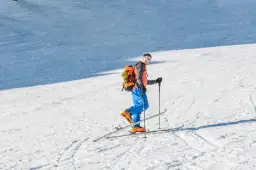 Narciarz z plecakiem na stoku, zastanawia się, ile waży but narciarski.