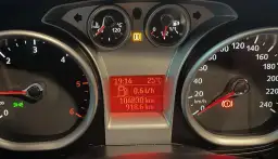 Deska rozdzielcza Ford Focus z kontrolkami: temperatura, paliwo, przebieg, prędkościomierz i kontrolka hamulca ręcznego.