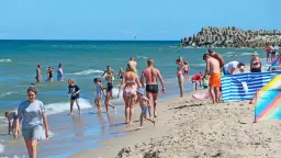 Ludzie kąpią się i spacerują po plaży nad morzem w słoneczny dzień.